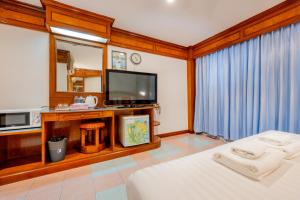 a bedroom with a bed and a tv and a mirror at Lamai Hotel in Patong Beach +23 photos