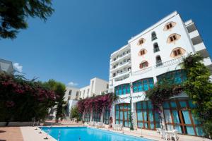 un hôtel avec une piscine en face d'un bâtiment dans l'établissement Hotel Degli Aranci, à Vieste