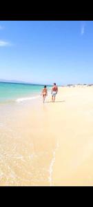 two people walking on a beach with the ocean at Nefeli in blue in Plaka