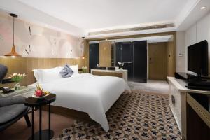 a bedroom with a large white bed and a living room at Paco Hotel Tiyuxilu Metro Guangzhou- 1 minute walk from the subway in Guangzhou