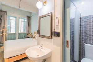 a bathroom with a bed and a sink and a mirror at Latima Boutique Hostel in Kanchanaburi