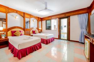 two beds in a room with windows at Lamai Hotel in Patong Beach