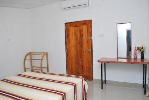a room with a bed and a table and a mirror at Fern Dale in Weligama