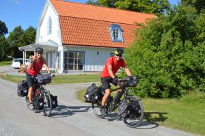 twee mensen die fietsen over een weg voor een huis bij Jädra Gårdshotel in Enköping