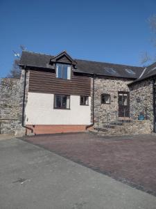 una casa in pietra con un vialetto di fronte di Shepherd's Watch Cottage - 5* Cyfie Farm with private hot tub a Llanfyllin