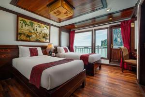 a bedroom with two beds and a balcony on a boat at Indochina Sails Ha Long Bay Powered by ASTON in Ha Long