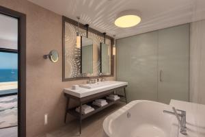 a bathroom with a tub and a sink and a mirror at The Westin Dragonara Resort, Malta in St. Julianʼs