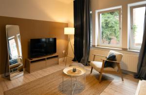 uma sala de estar com uma televisão, uma cadeira e uma mesa em Huge apartment with Sauna and free parking em Duisburg