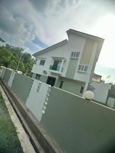 a large white house behind a fence at Bahagia Makmur Homestay in Temerloh