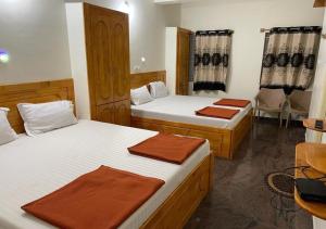 1 dormitorio con 2 camas, mesa y sillas en Yelagiri Naksha Tree Hotels en Yelagiri