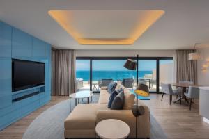 a living room with a couch and a television at The Westin Dragonara Resort, Malta in St. Julianʼs