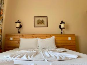 a bed with white sheets and two lights on the wall at Eco complex Miramar in Mineralni Bani