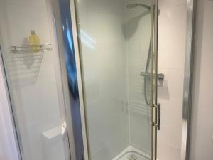 a shower with a glass door in a bathroom at Lovely Self Contained Loft Studio - 33AS4 in London