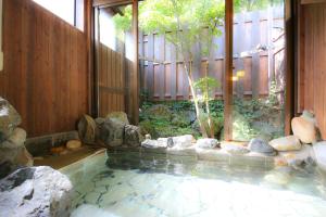 a pool of water with rocks in a house at Hotel Soyokaze in Hakuba