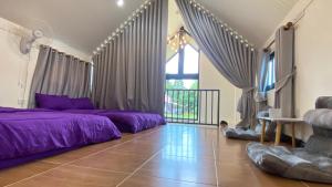 a living room with purple beds and a window at บ้านนอร์ดิกวิลล่า เขาค้อ in Ban Thung Samoe