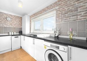 une cuisine avec un lave-linge et un mur en briques dans l'établissement Berwick Apartment by Klass Living Coatbridge, à Coatbridge