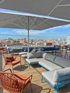un patio con sofá, sillas y sombrilla en Wine & Books Porto Hotel, en Oporto