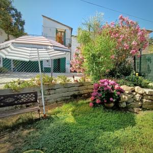 een tuin met een bank, een parasol en bloemen bij Casa rustica tra mare e collina in Morciano di Romagna