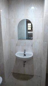 a white bathroom with a sink and a mirror at Apartemen Skylounge Makassar in Sudiang