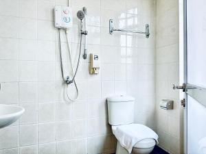 y baño con ducha, aseo y lavamanos. en Asphodel Inn en Singapur