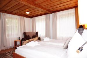 a bedroom with two beds and a chair and windows at Ferienwohnung Aignerhof in Schellgaden