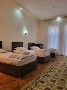 3 łóżka w pokoju z drewnianą podłogą w obiekcie Dili Orom Hotel w mieście Buchara