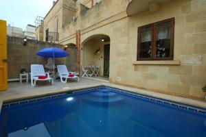 uma piscina com duas cadeiras e um guarda-sol em W, Villagg San Guzepp em Qala