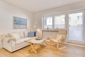 un soggiorno con divano bianco e tavolo di Urlaubsmanufaktur a Norderney