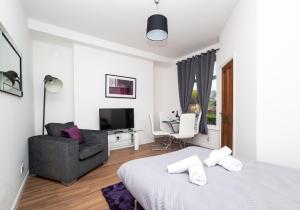 Habitación blanca con cama, silla y TV. en Cosy Apartment by Klass Living Bellshill en Bellshill