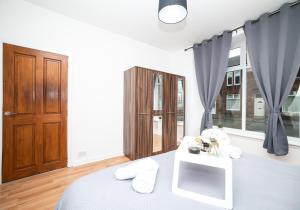 a bedroom with a bed with a wooden door and windows at Cosy Apartment by Klass Living Bellshill in Bellshill