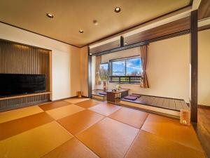 een woonkamer met een groot raam en een flatscreen-tv bij Yukai Resort Dogo Saichoraku in Matsuyama