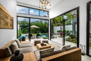 een open woonkamer met grote ramen en een woonkamer met een bank bij Villa Jimeste by BaliSuperHost in Ubud