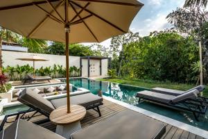 een terras met stoelen en een parasol naast een zwembad bij Villa Jimeste by BaliSuperHost in Ubud +31 foto's