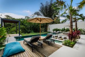 een patio met stoelen en een parasol naast een zwembad bij Villa Jimeste by BaliSuperHost in Ubud