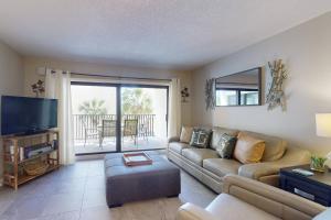 a living room with a couch and a flat screen tv at 210 - Sandy Shores in St. Pete Beach