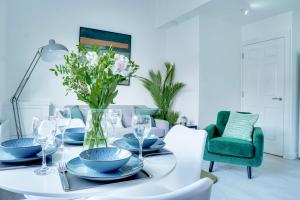 una sala da pranzo con tavolo bianco e vaso di fiori di Modern 2 bedroom flat - 15 minutes to Liverpool a Birkenhead