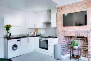 a kitchen with a brick wall with a tv on it at Modern 2 bedroom flat - 15 minutes to Liverpool in Birkenhead +21 photos