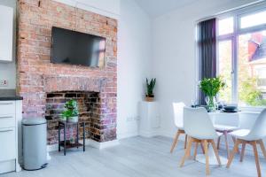 a living room with a brick fireplace and a table and chairs at Modern 2 bedroom flat - 15 minutes to Liverpool in Birkenhead