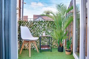 uma cadeira branca sentada numa varanda com plantas em Modern 2 bedroom flat - 15 minutes to Liverpool em Birkenhead