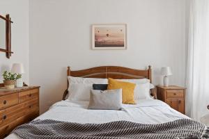 een slaapkamer met een bed met witte lakens en gele kussens bij MaCri di TSS' - Per coppie, colazione in balcone, intimo e relax in Levico Terme