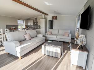 a living room with two white couches and a kitchen at 35 Delamere Point in Northwich