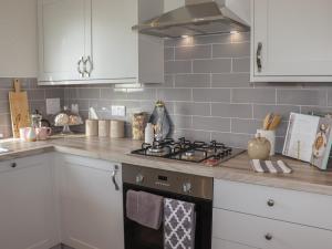 La cuisine est équipée de placards blancs et d'un four avec plaques de cuisson. dans l'établissement 35 Delamere Point, à Northwich