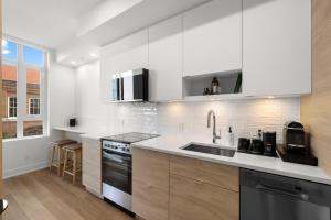 een witte keuken met een wastafel en een fornuis bij Brand New Building! Modern, Conveniently Located 1 Bedroom Condo. in Victoria