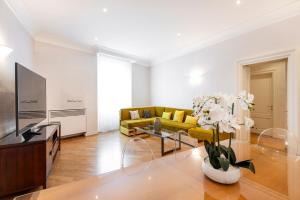 sala de estar con sofá amarillo y TV en Milan Royal Suites - Centro Brera, en Milán