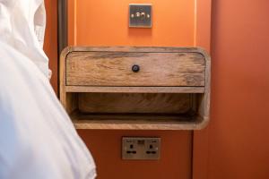 a nightstand with a wooden drawer next to a bed at The Sheep and Penguin in Wells