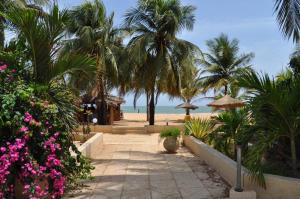 a pathway leading to the beach with palm trees and pink flowers at Appartement à Saly in Saly Portudal