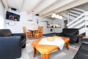 a living room with leather furniture and a table at Ferienhaus Deichliebe in Bensersiel