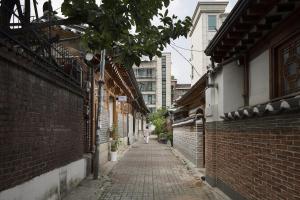 a person walking down a brick alley at Renewal Open!!! Entire Place, Traditional Stay Xiwoo , 時雨 시우 한옥독채 in Seoul