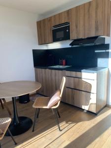 eine Küche mit einem Tisch, einem Tisch und Stühlen in der Unterkunft Studio avec Balcon Pra chauvet in Uvernet