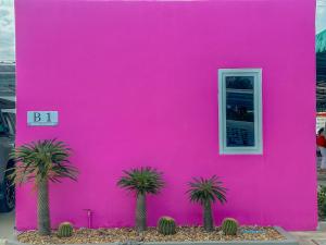 un edificio rosa con palmeras delante en Klong Zand Resort en Rayong